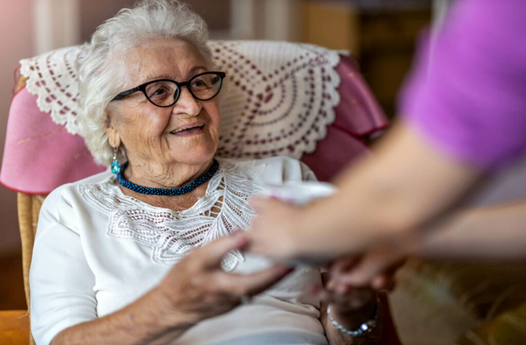 a senior woman with dementia sits in a pink chair