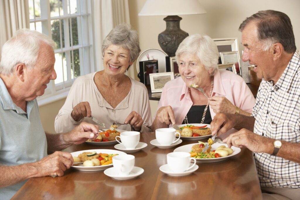 A group of 4 seniors sitting at a table enjoying a healthy meal.