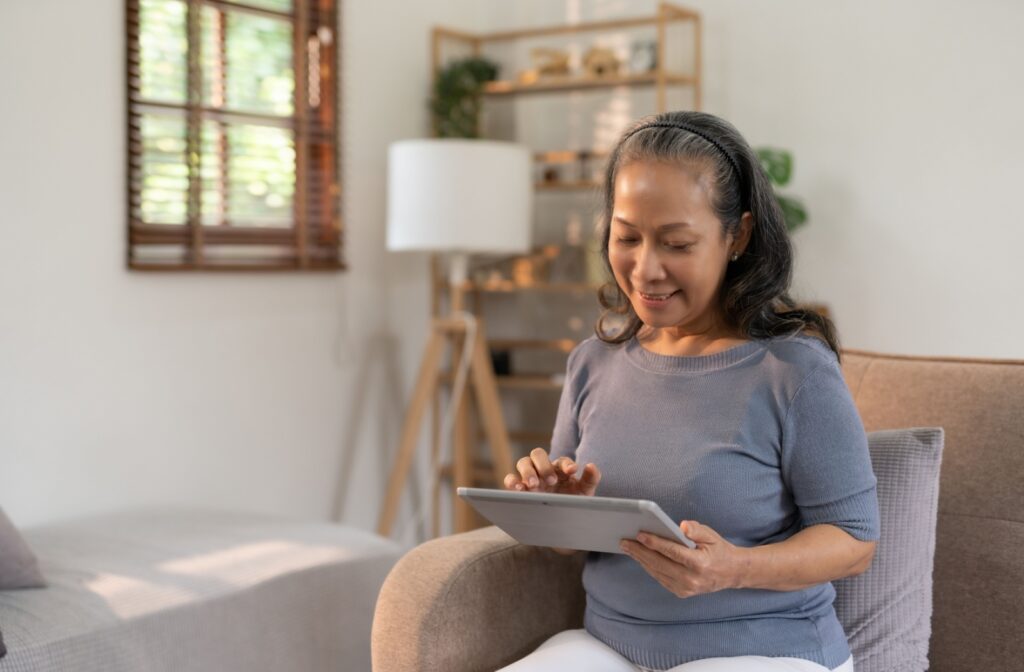 Senior person sitting in an arm chair using a tablet.